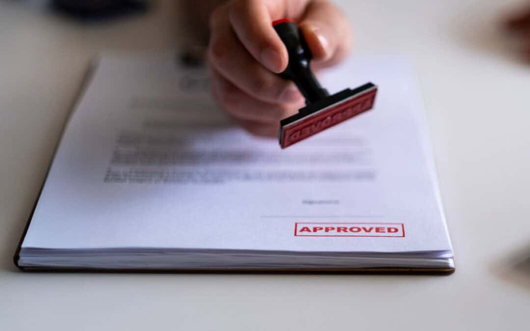 Person stamping an approved document with a red rubber stamp.