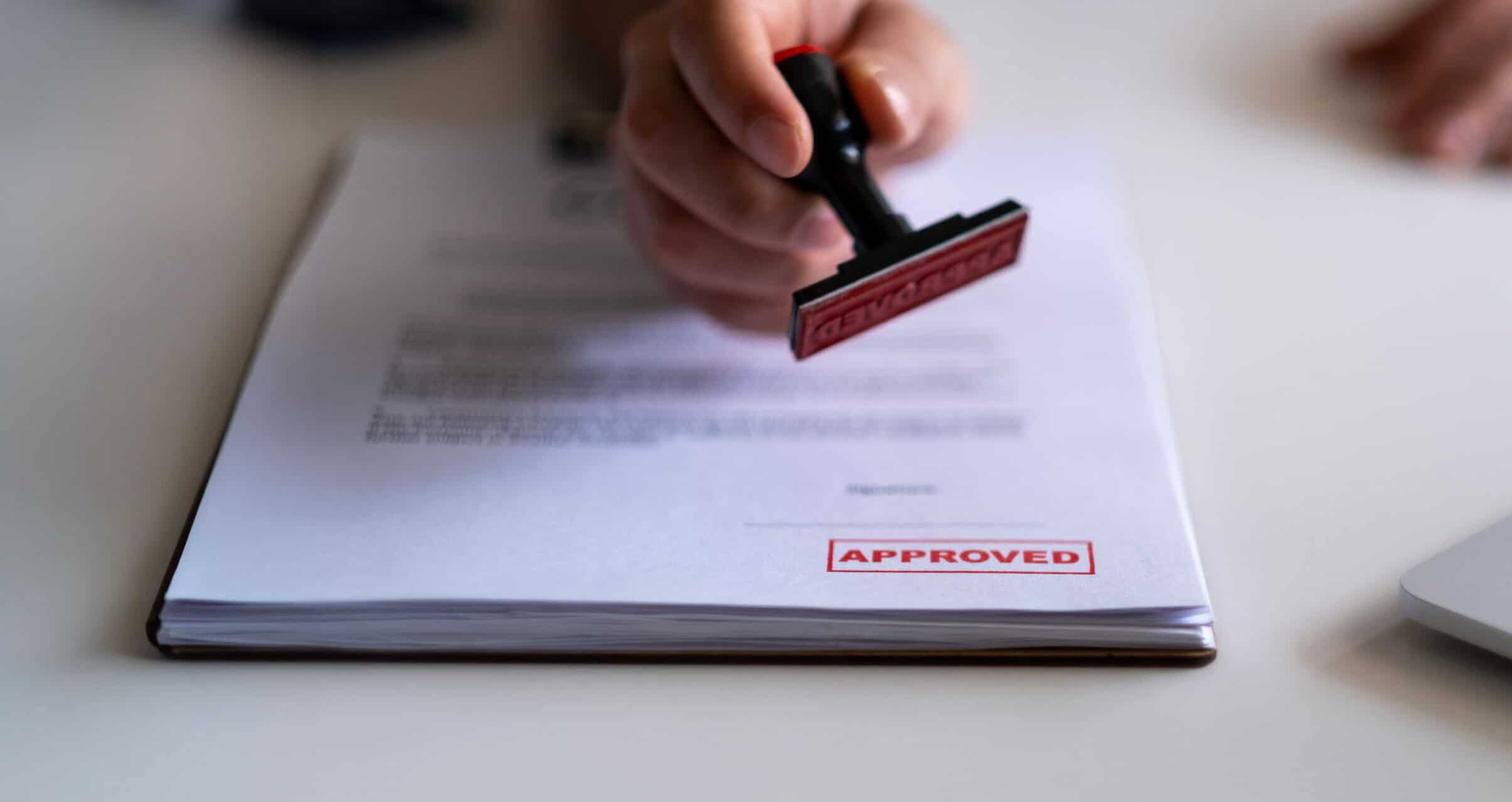 Person stamping an approved document with a red rubber stamp.