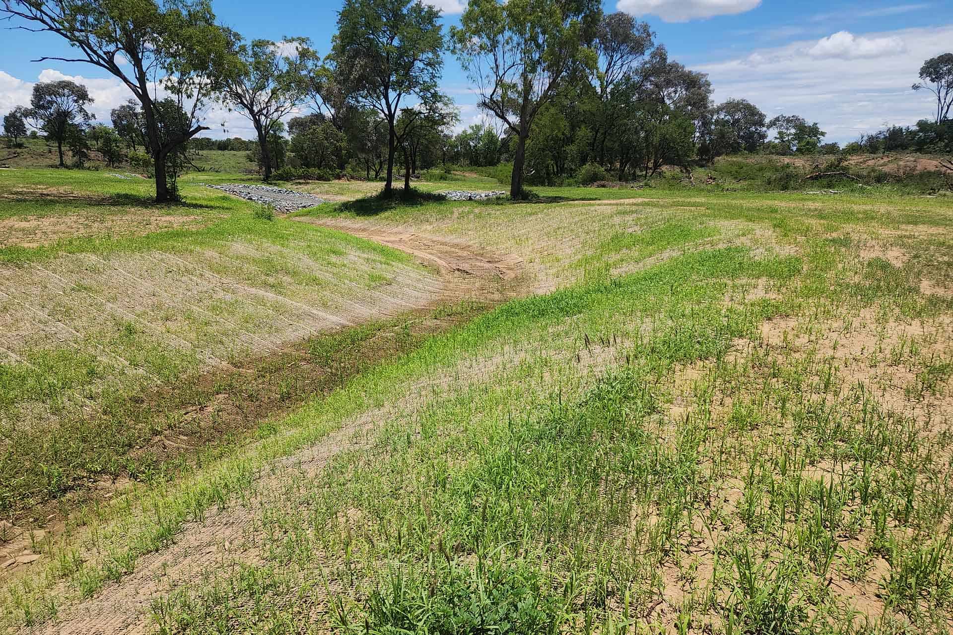 Completed drainage works at Havilah Station showing a vegetated drainage channel and rehabilitated surrounding area.