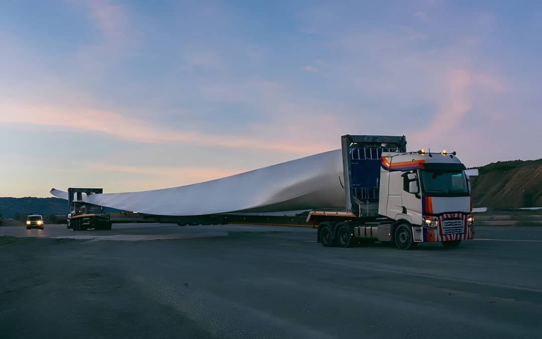 Truck transporting a wind turbine blade indicative of swept path road upgrade works.