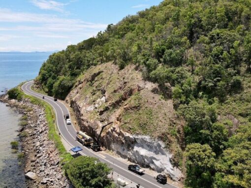 Coastal section of the Captain Cook Highway winding between rocky headlands and tropical vegetation.